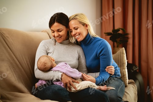 Preview: Happy lesbian couple taking care of her small baby at home - LGBT Family and maternity concept