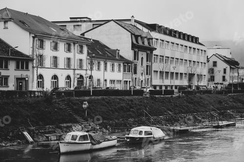 Preview: Grayscale shot of the boats on the river against the buildings on the shore.