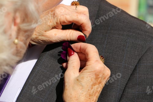 Preview: Elderly woman pinning flower on lapel of man’s suit.