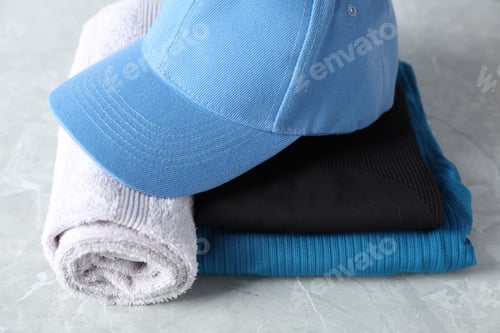 Preview: Stylish sportswear and towel on light grey table, closeup
