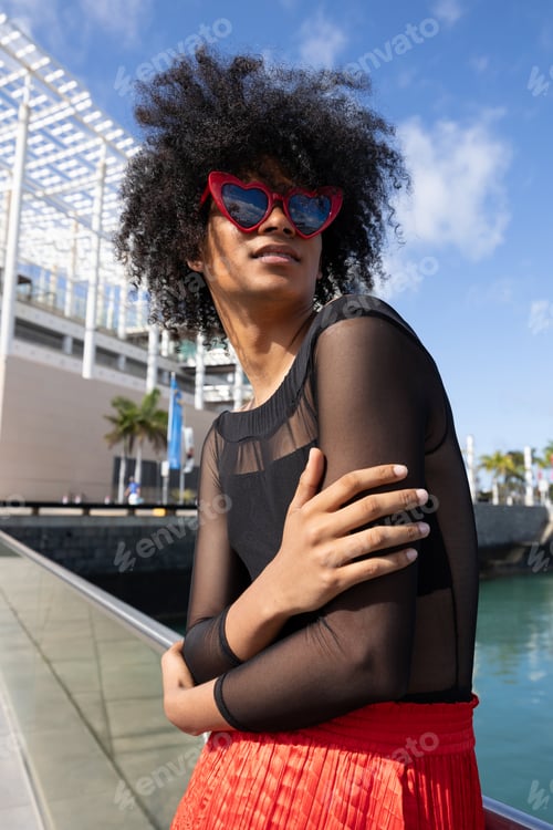 Preview: portrait of non binary gender person of large afro with red heart glasses