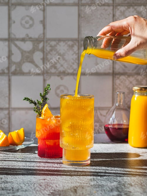 Preview: Two glasses with yellow mango juice and red syrup. The drinks are decorated with juniper sprigs.