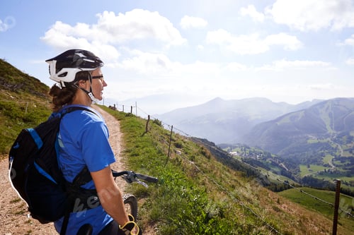 Preview: Cyclist wearing cycling helmet looking at view of mountains