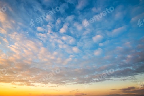 Preview: Dramatic sunset landscape with puffy clouds lit by orange setting sun and blue sky