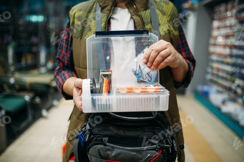 Preview: Angler holds box with hooks and baubles