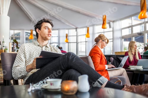 Preview: Businessman holding digital tablet while colleagues working in background
