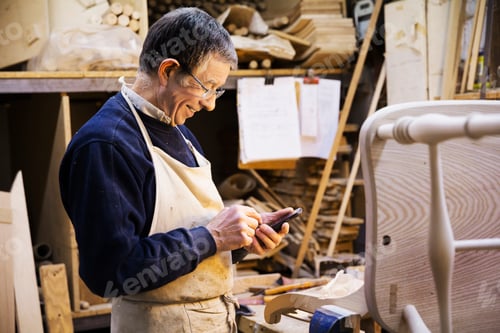 Preview: Man standing at a work bench in a carpentry workshop, working on a wooden chair.