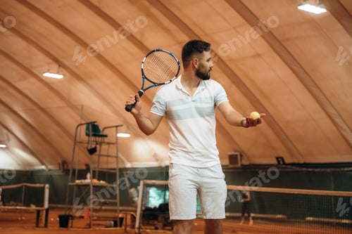 Preview: Man Holding Tennis Ball and Racquet Indoors