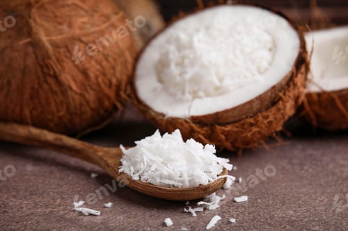 Preview: Coconut flakes and spoon on brown table, closeup