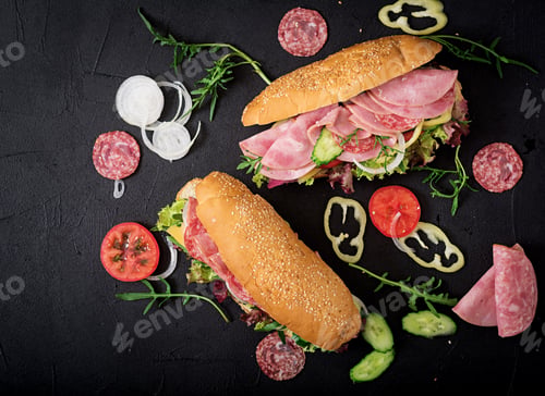 Preview: Big sandwich with ham, salami, tomato, cucumber and herbs. Flat lay. Top view