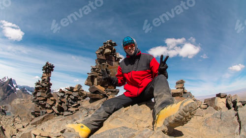 Preview: Young climber sitting on the top of a rocky mountain during a sunny day