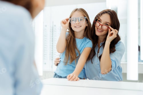 Preview: Happy mother and daughter wearing glasses in optics store