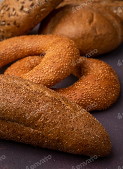 Preview: side view of seeded baguette with bagels and cobs on maroon background