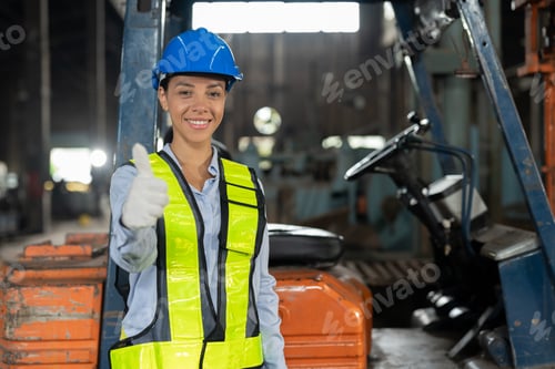 Preview: African American female driver forklift truck showing thumbs up in heavy metal industrial factory