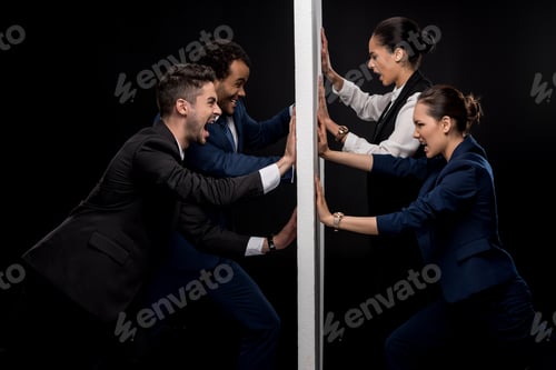 Preview: Group of angry businessmen ready to fight with businesswomen from separated wall isolated on black