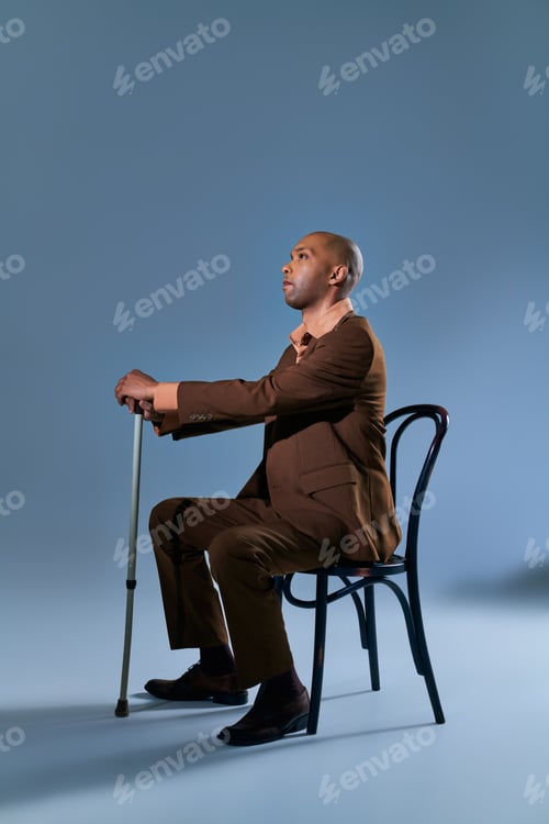 Preview: Man in Brown Suit Seated Holding Walking Cane