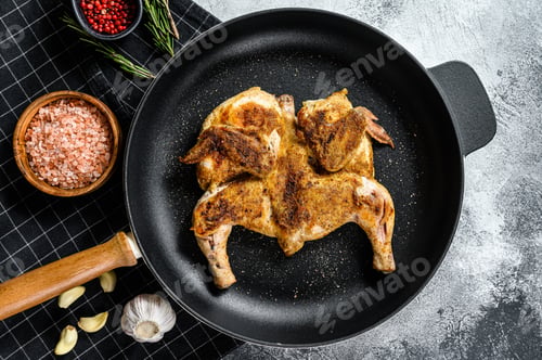 Preview: Grilled fried roast Chicken Tabaka in a pan. Gray background. Top view