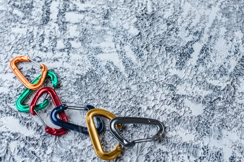 Preview: Isolated photo of climbing equipment. Part of carabiner lying on the white and grey colored surface