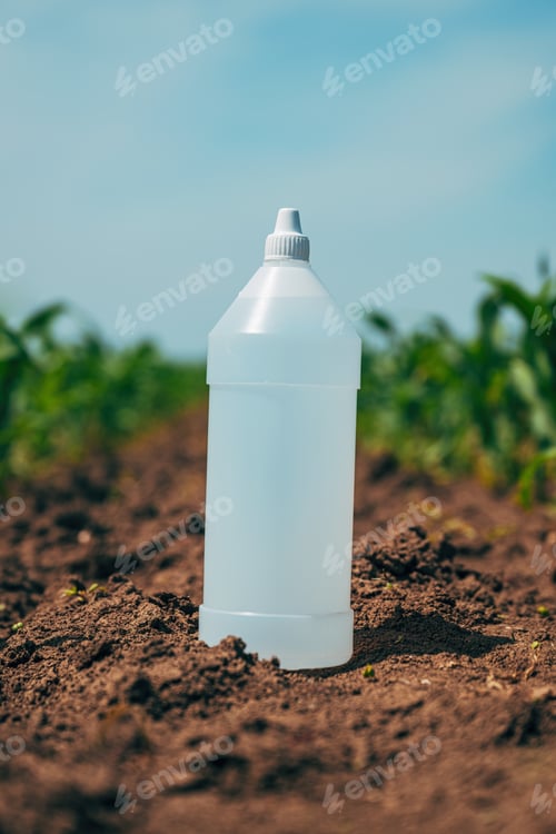 Preview: Vertical shot of herbicide bottle in perfectly clean corn plantation field