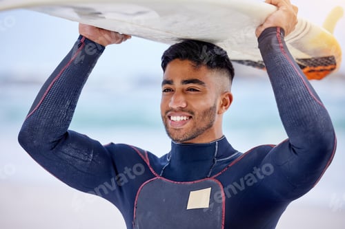 Preview: Keep it simple - surf more. Shot of a handsome young man carrying a surfboard at the beach.