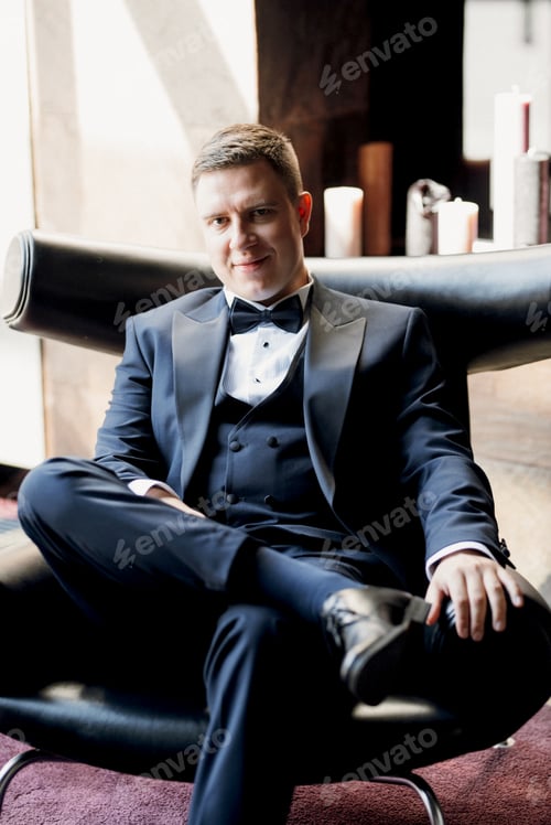 Preview: portrait of groom in blue tuxedo in hotel
