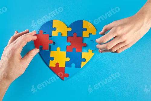 Preview: Father and autistic son hands holding jigsaw puzzle heart shape. World Autism Awareness Day