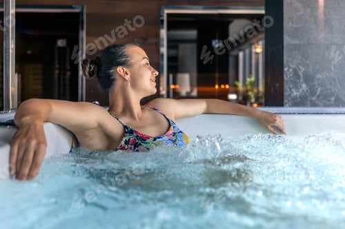 Preview: Woman relaxing in hot tub at modern spa with bubbles. Quiet relax moment.