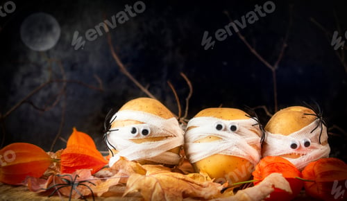Preview: Halloween food. Spooky potatoes wrapped in medical bandages in autumn leaves on a dark night.