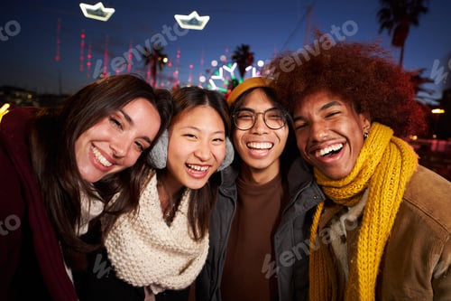 Preview: Four happy friends taking smiling selfie looking camera standing together at night outdoor.