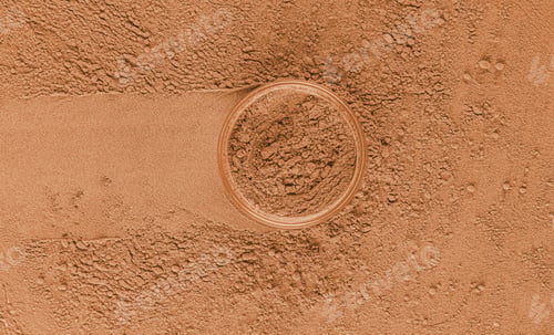 Preview: A cosmetic jar with loose powder in a bronze or brown tone stand on the sample with a trace of a jar