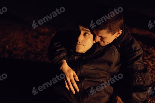 Preview: Men hugging and sitting on ground on field at night