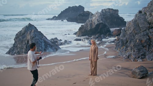 Preview: Man professional shooting model on ocean beach. Shore girl in suit posing camera