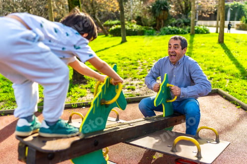 Preview: Grandfather and grandson playing on a seesaw in a sunny park