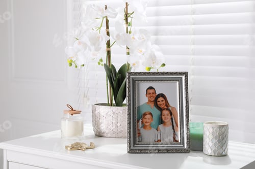 Preview: Framed family photo and orchid flower on white table indoors