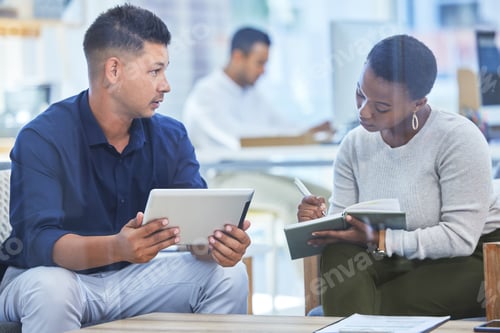 Preview: Shot of a man holding a digital tablet while his colleague takes notes
