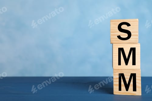 Preview: Cubes with abbreviation SMM (Social media marketing) on blue table. Space for text