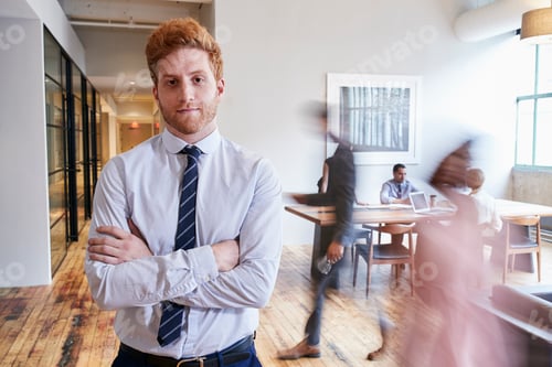 Preview: Portrait of young red haired man in a busy modern workplace