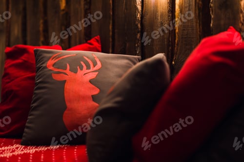Preview: Deer head on red hand made pillow wooden background in interior