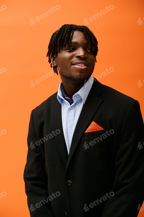 Preview: Handsome young man showcases stylish attire against vibrant orange backdrop