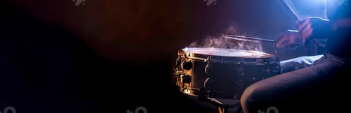 Preview: A man plays a snare drum on a dark background, copy space.