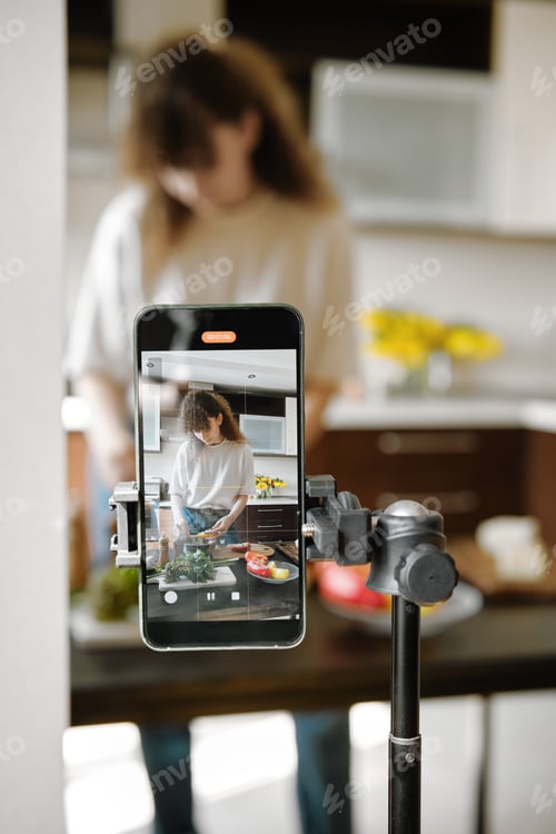 Preview: Smartphone recording a focused woman preparing food in a modern kitchen