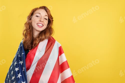 Preview: Happy redheaded woman wrapping with a north america national flag