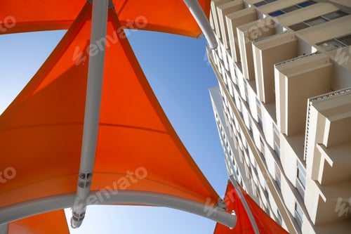 Preview: Colorful orange sun shade against blue sky in Abu Dhabi, looking up, abstract street