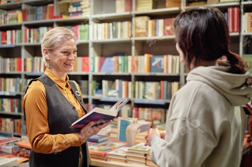 Preview: Middle Aged Caucasian Woman Smiling While Recommending Book to Young Adult