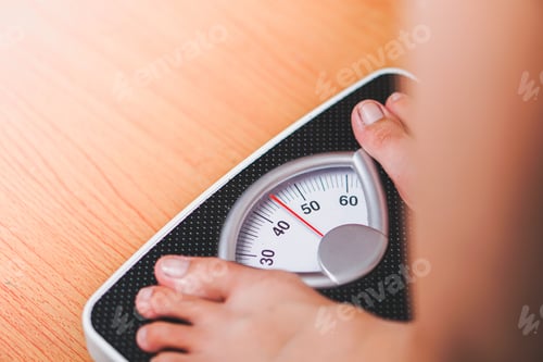Preview: feet standing on a black scale weighing machine with a wooden base
