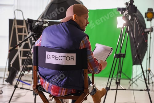 Preview: Movie director sitting on chair in modern film studio, back view
