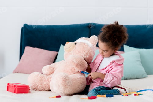 Preview: Adorable african american kid examining teddy bear
