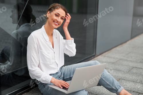 Smiling Woman Works on Laptop in Urban Setting