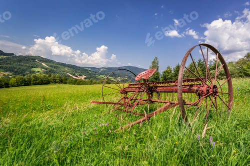 Preview: Red rake in a field in the mountains