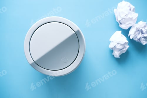 Preview: crumpled paper ball in a bin on blue background top view